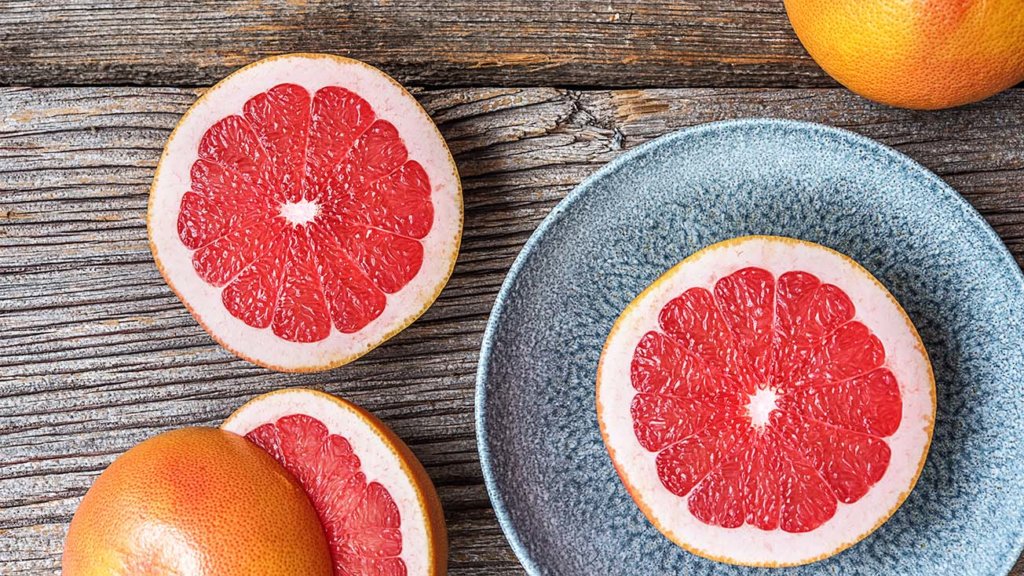  Sommer-Lebensmittel: Saftige Grapefruit aufgeschnitten auf Teller