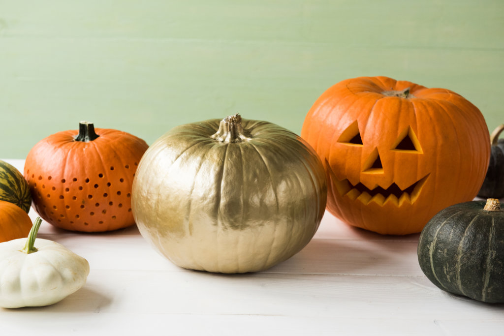 Saisonal essen Halloween: Ausgeschnitzte und angemalte Kürbisse als Deko